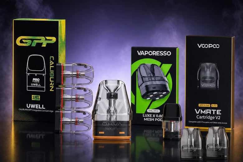 A promotional display of vape accessories and parts on a dark reflective surface with a smoky purple background. Visible products include a green and black Uwell Caliban box, a clear and black Luxx S-Blue pod, a clear and black VMRTE pod, and other small vape components.